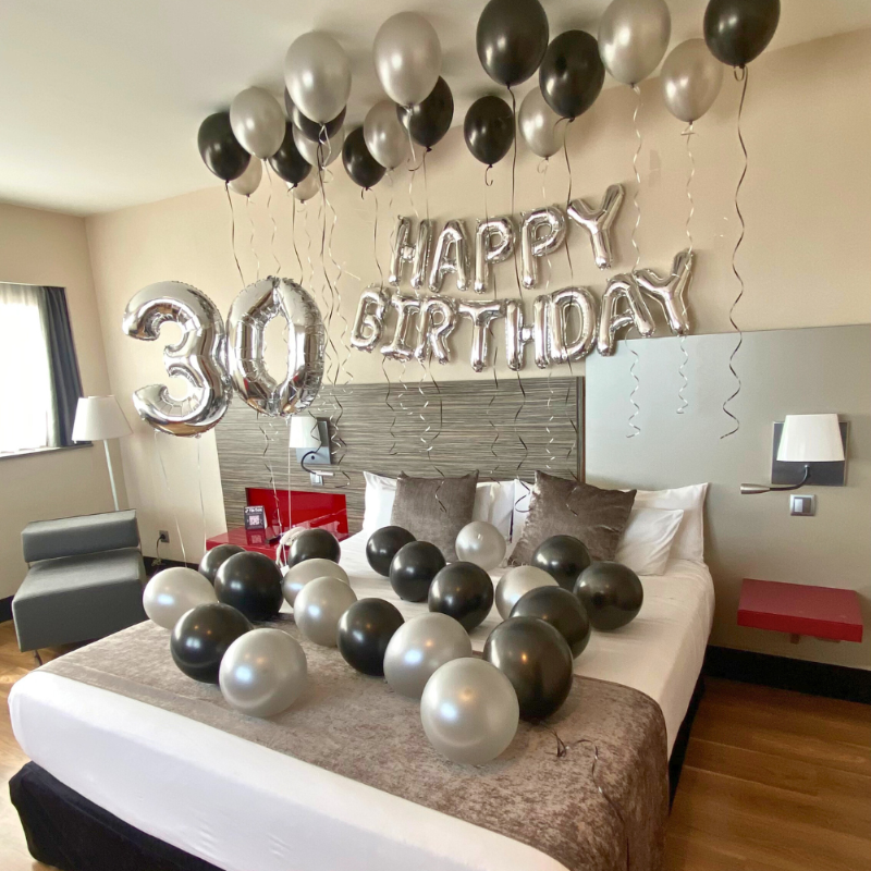 Habitación de hotel decorada con globos plateados por cumpleaños número 30º