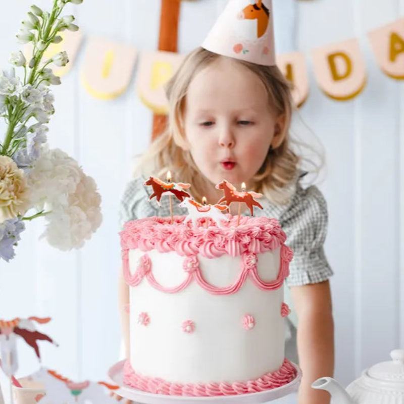 niña solanda un pastel con velas de caballo