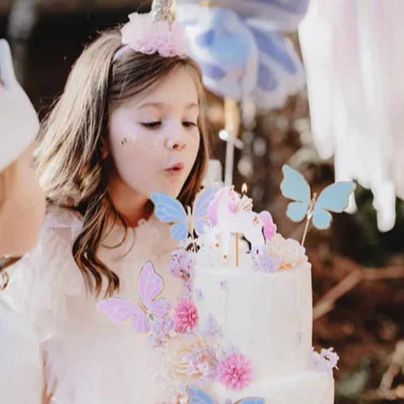 Niña soplando vela de unicornio blanca