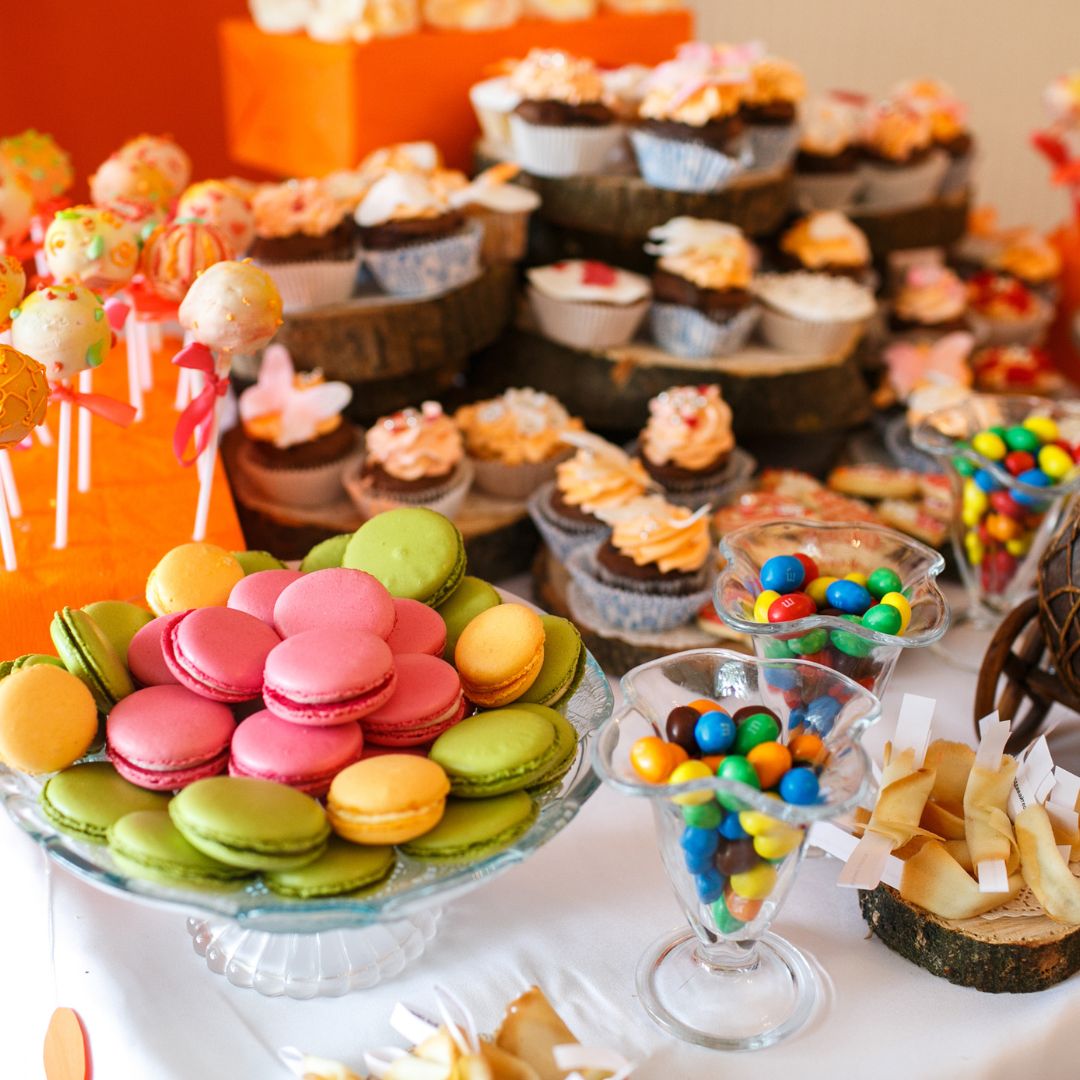 Candy bar colorido con macarons, cupcakes, paletas y dulces variados, perfecto para complementar cualquier fiesta o celebración especial.